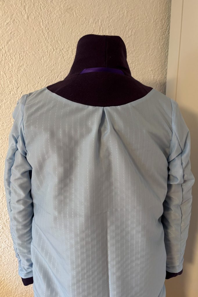 Rückansicht des Futters mit Falte in der hinteren Mitte und leicht faltig gelegten Ärmeln.